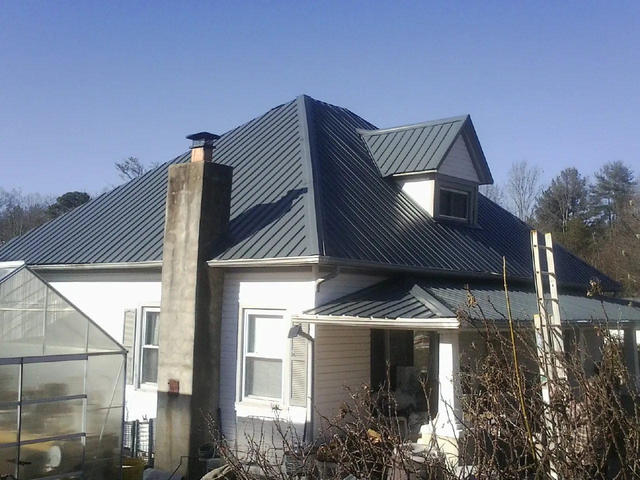 Dark blue standing seam metal roof on a white farmhouse with dormer — Slate & Tile Roof Repair by Roofing Brothers in Brodhead