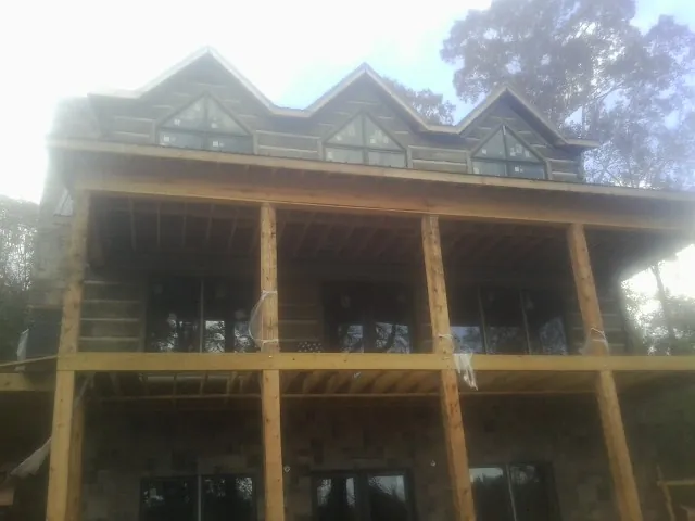 Dormers and porch framing on a large log home under construction — Roof Coating work by our crew in Brodhead