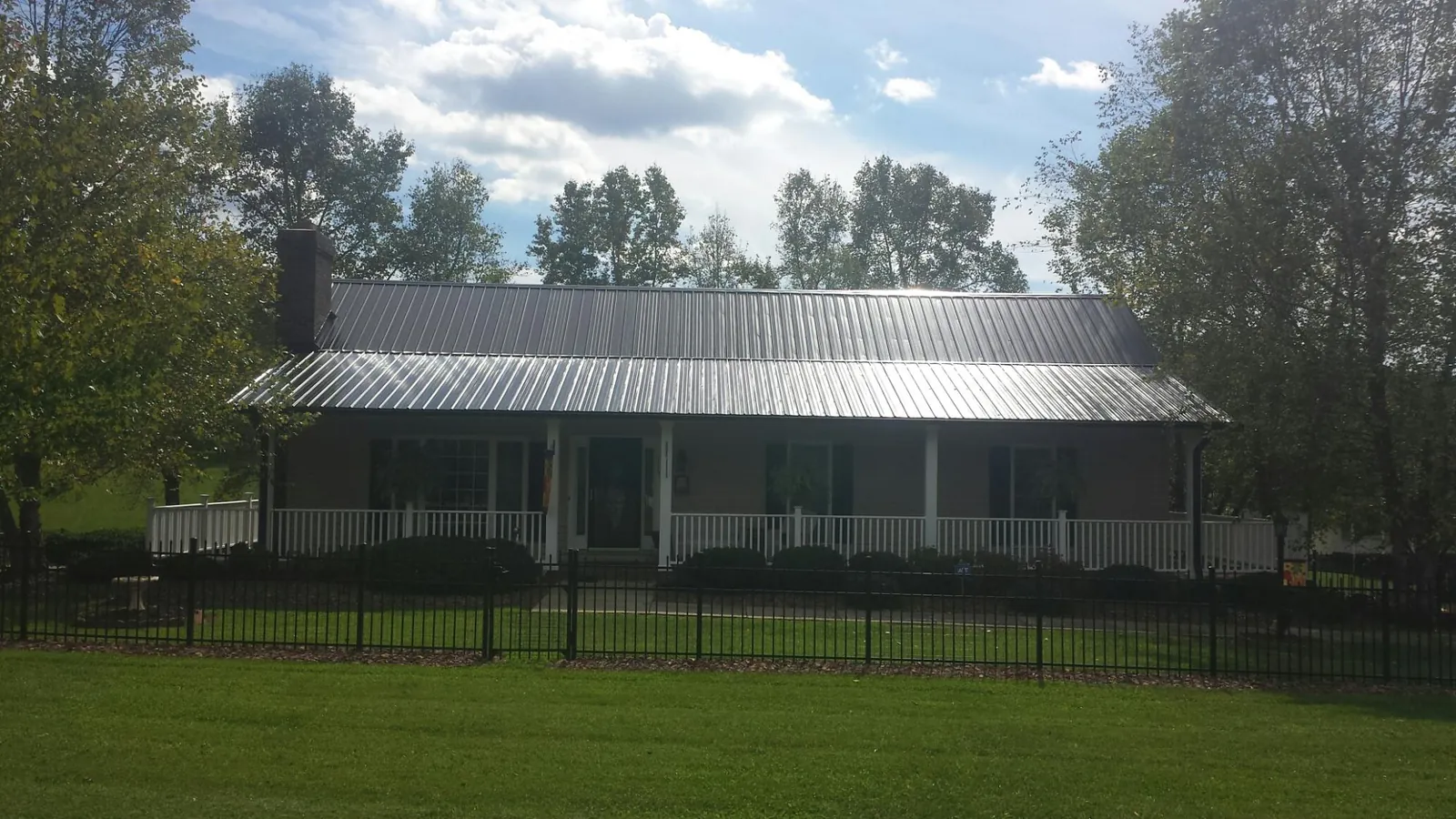 Gray metal roof on a brick ranch with a full width front porch — Gutter Guard Installation work by our crew in Brodhead