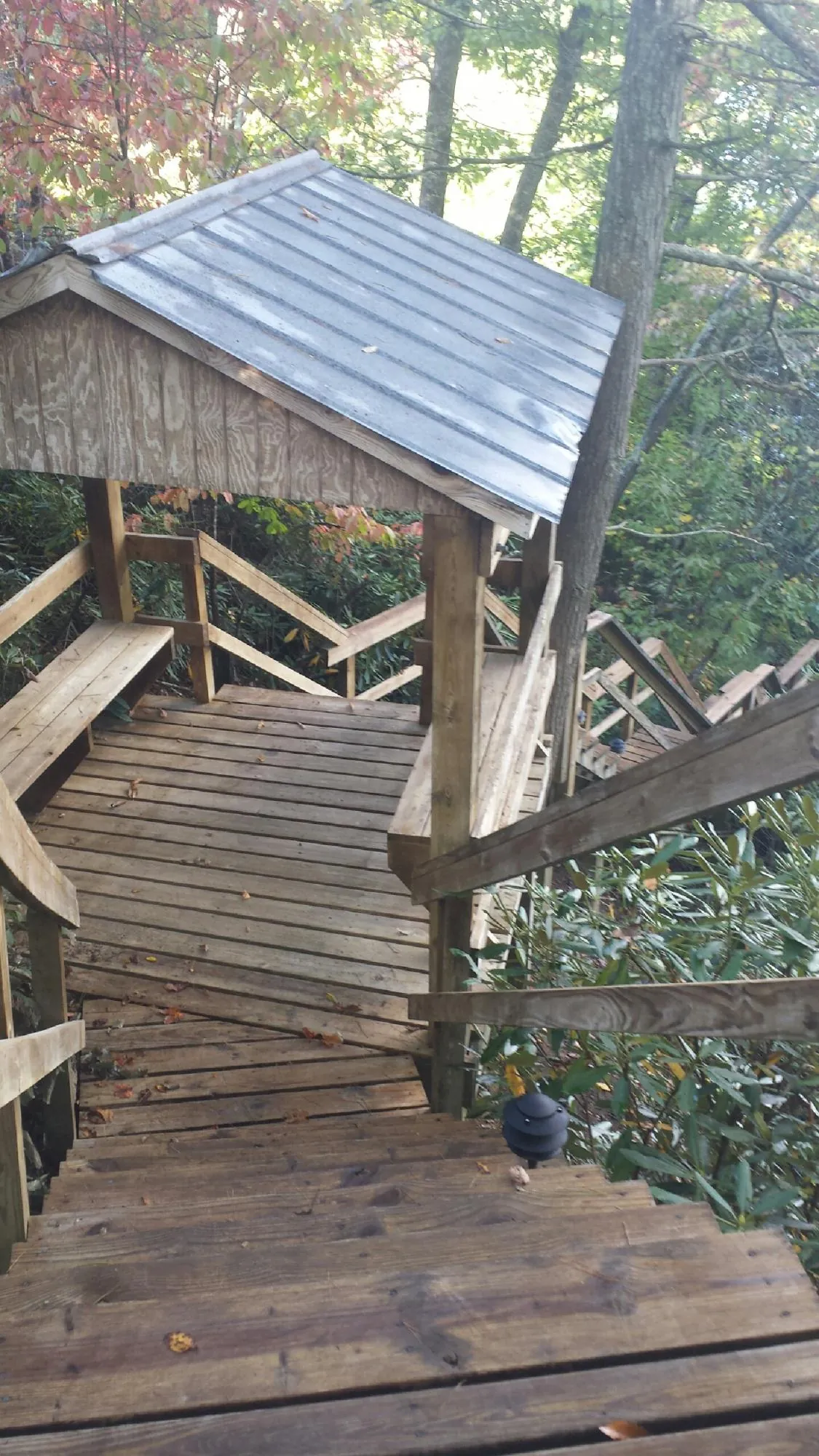 Metal roofed shelter over wooden steps on a wooded walkway — Skylight Repair & Installation work by our crew in Brodhead