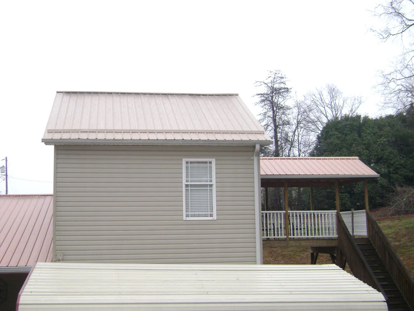 Tan metal roofs on a two story addition and attached porch, from a Roof Replacement job in Brodhead